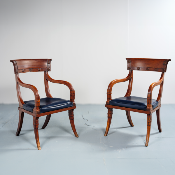 Fauteuils attribués Maison Jansen acajou dossier concave fleurs sculptées galette cuir bleu piètement en sabre